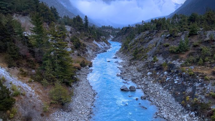 Río de aguas azules que atraviesa un valle montañoso con bosque