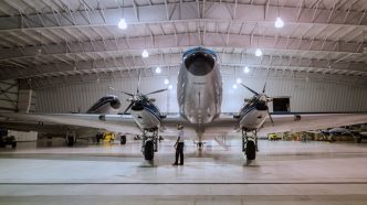 Aeronave de hélice en un hangar con un técnico frente a ella