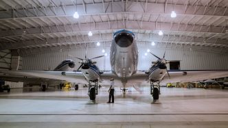 Aeronave de hélice en un hangar con un técnico frente a ella