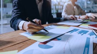 Dos ejecutivos analizan gráficas y documentos sobre una mesa de trabajo