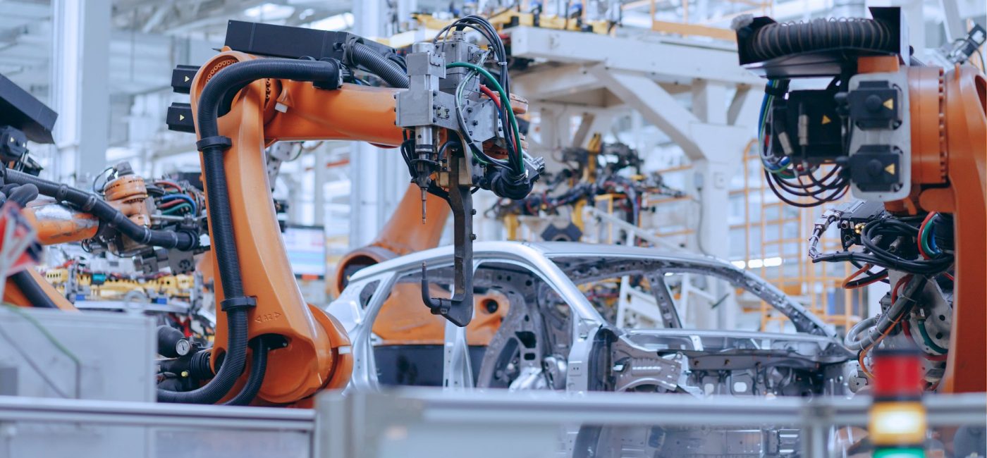 Brazos robóticos naranjas ensamblando un vehículo en una línea de producción automotriz
