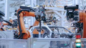 Brazos robóticos naranjas ensamblando un vehículo en una línea de producción automotriz