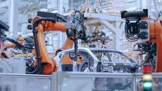 Brazos robóticos naranjas ensamblando un vehículo en una línea de producción automotriz