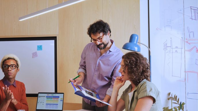 Equipo de tres profesionales revisando material junto a un pizarrón en una oficina